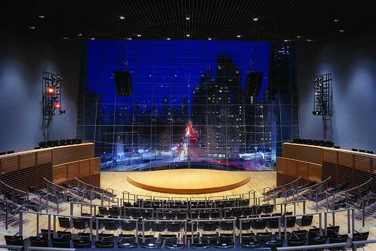 Theater with stage and floor to ceiling windows in background